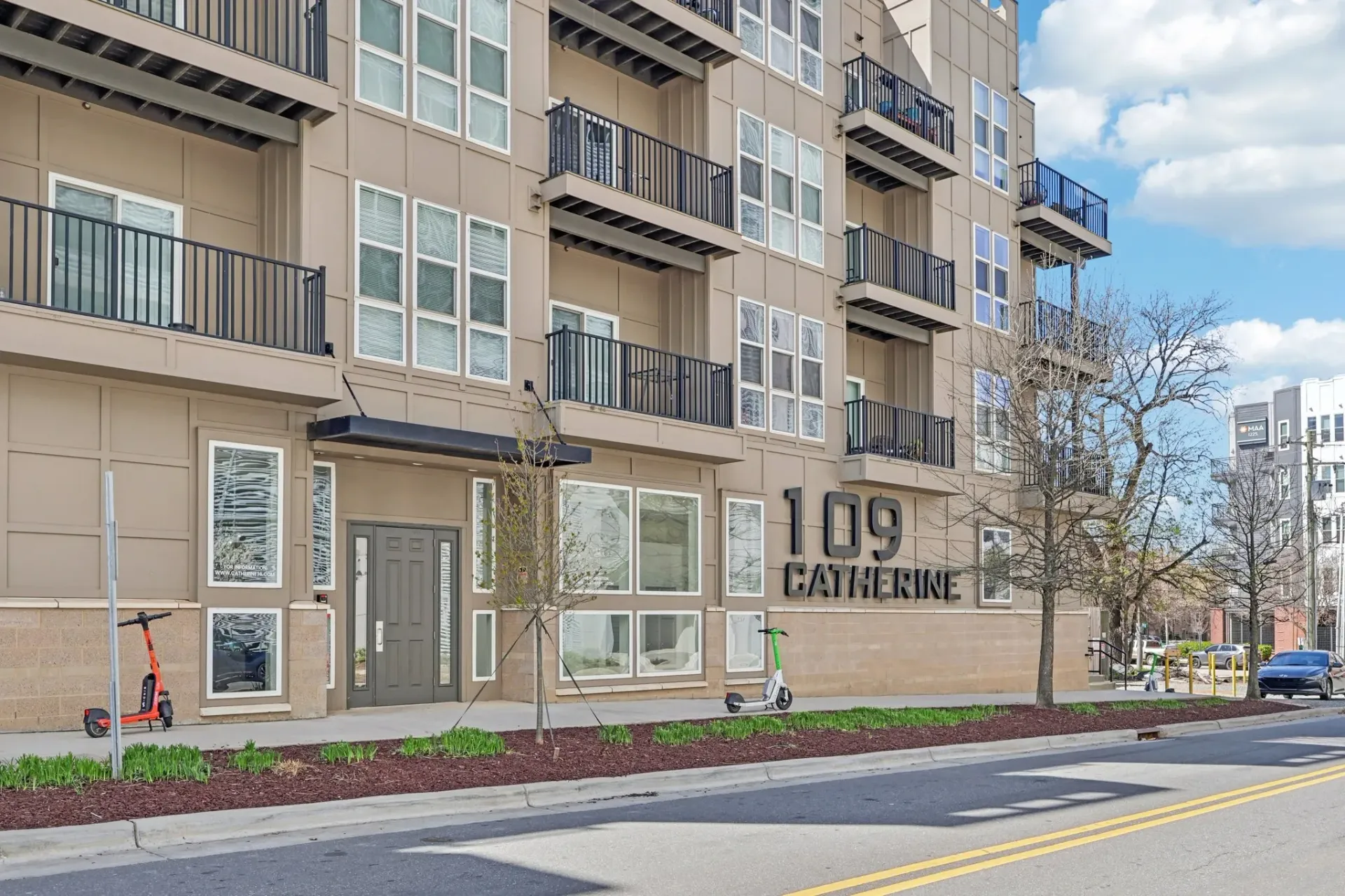 Exterior of the 109 Catherine apartment building with signage and scooters.