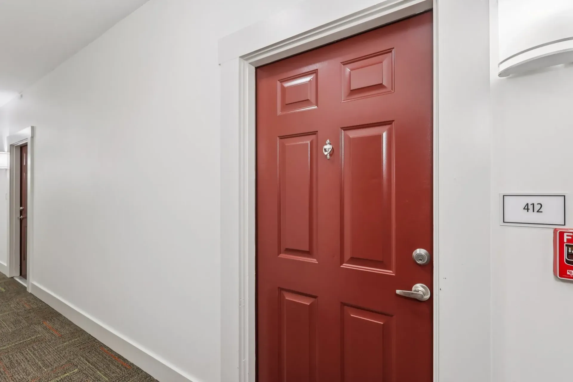 Hallway with red apartment doors and room number 412.