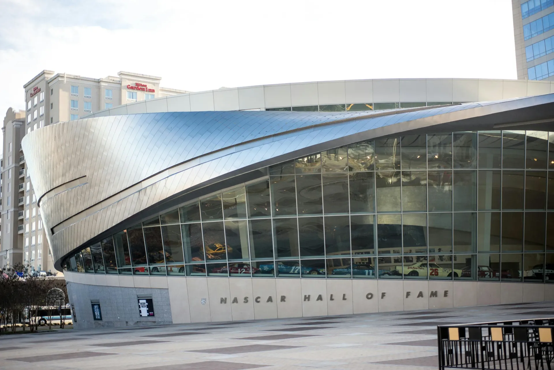 NASCAR Hall of Fame building exterior with cars displayed inside.