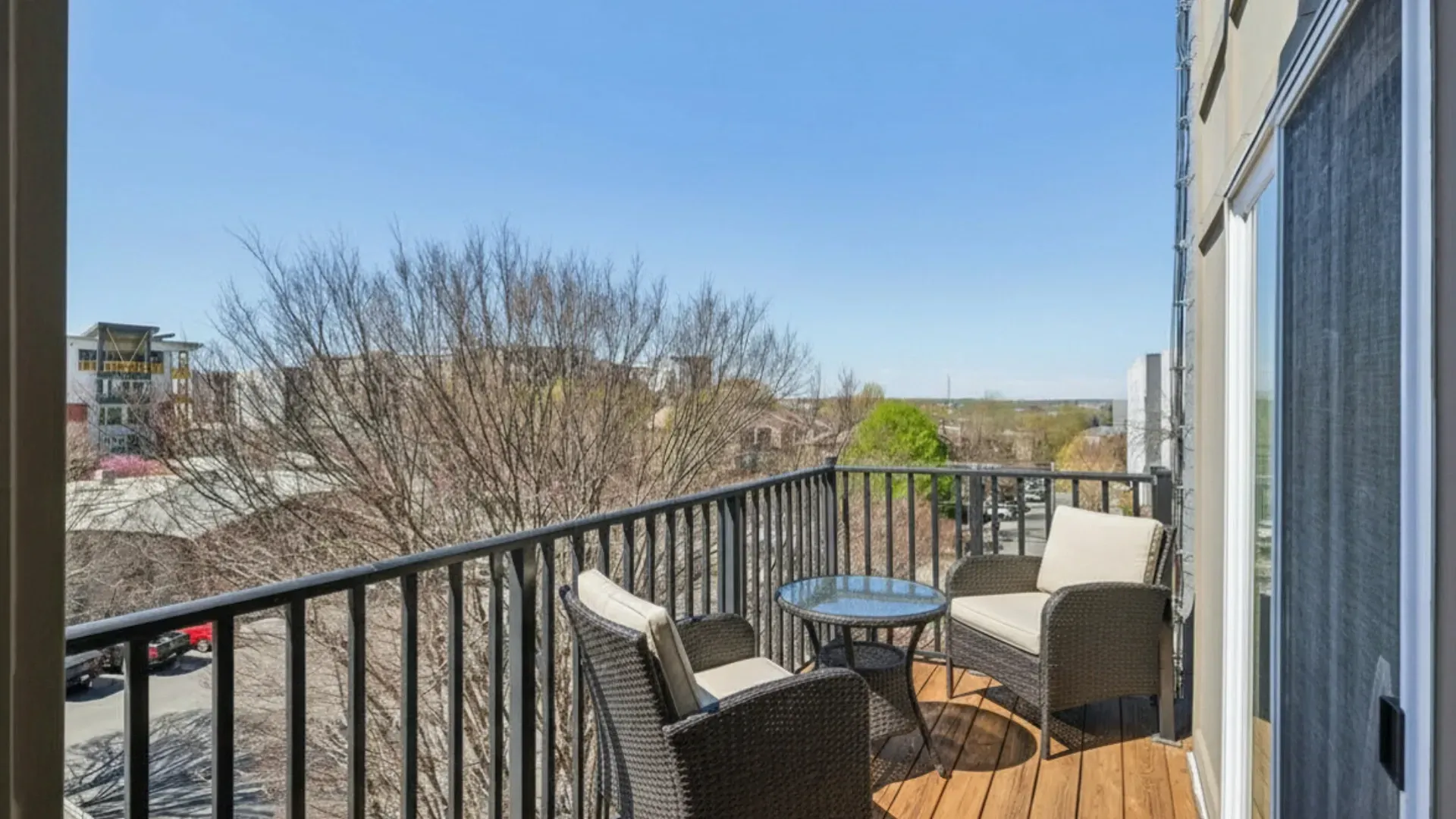 Balcony with two chairs, a small table, and a view of the city.