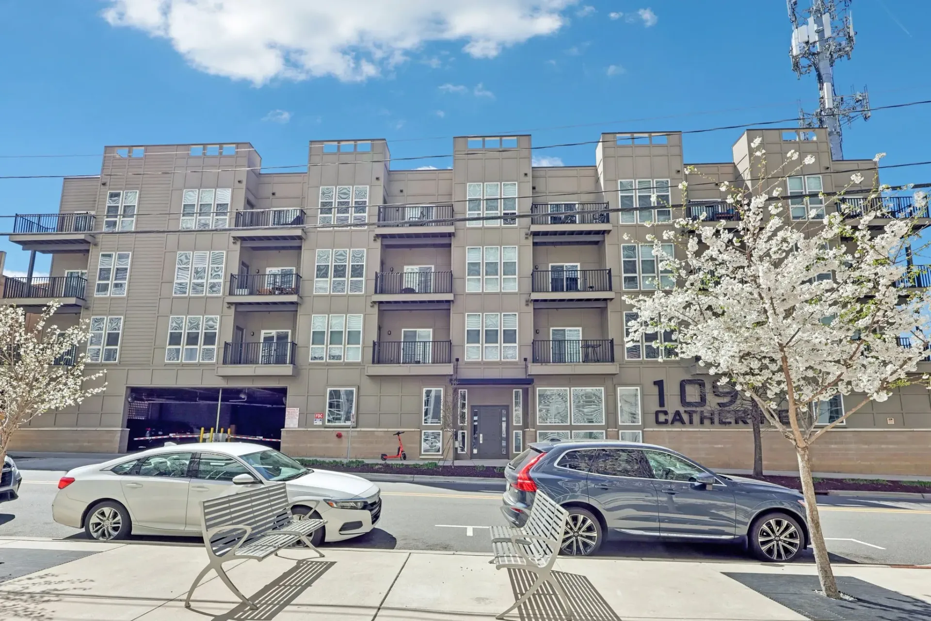 Apartment building exterior with balconies and cars parked out front.