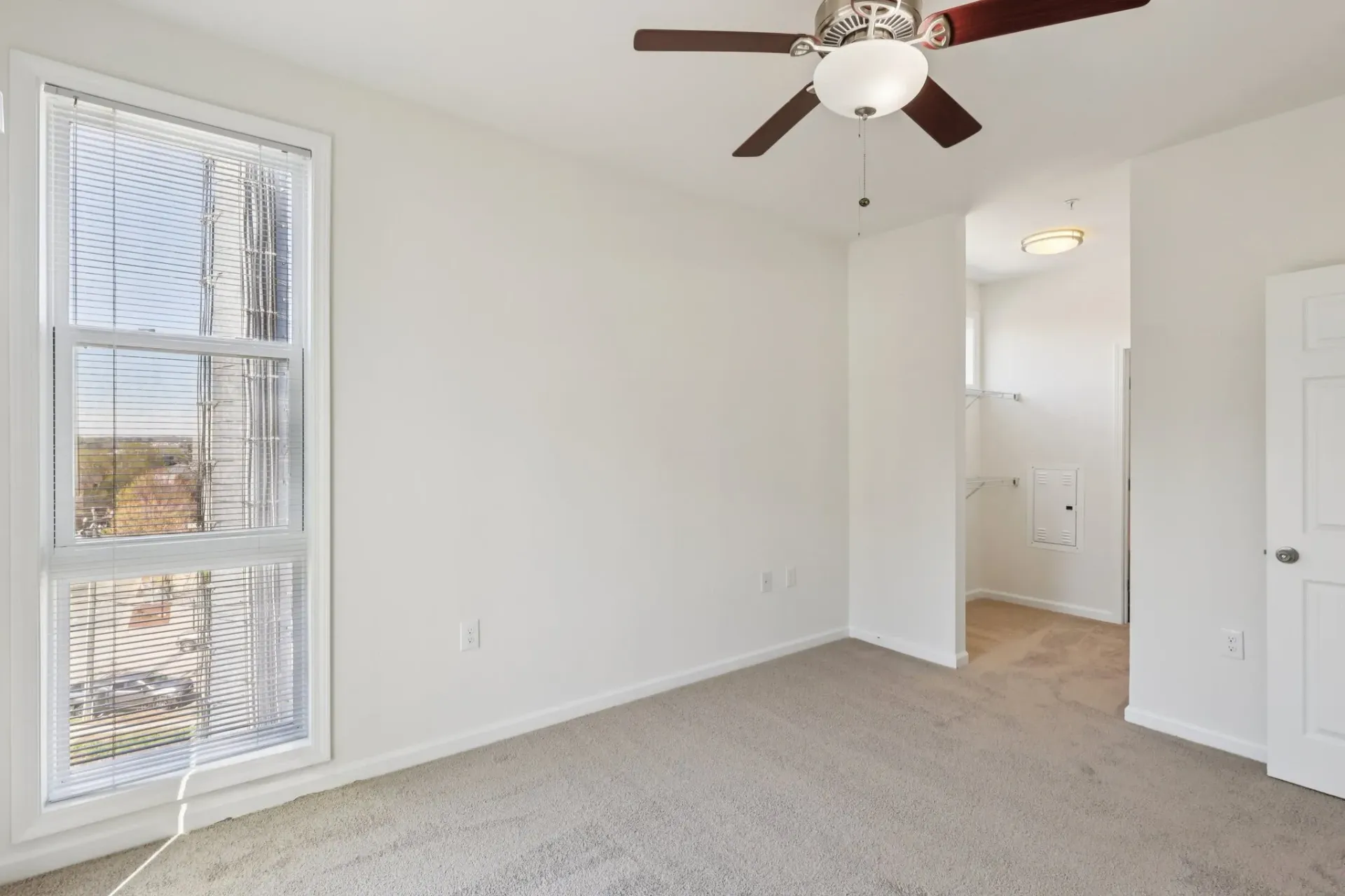 Bedroom with a ceiling fan, large window, and closet entrance.