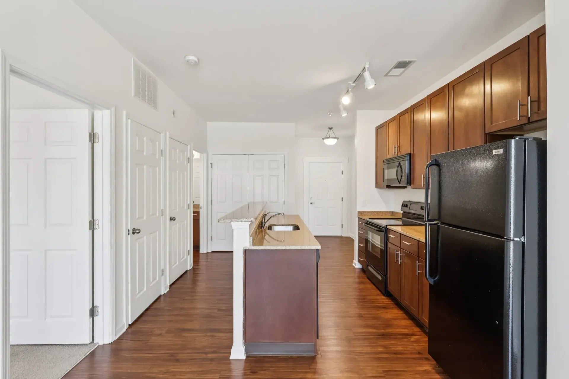 Modern kitchen with dark wood cabinets, granite countertops, stainless steel appliances, and an island.