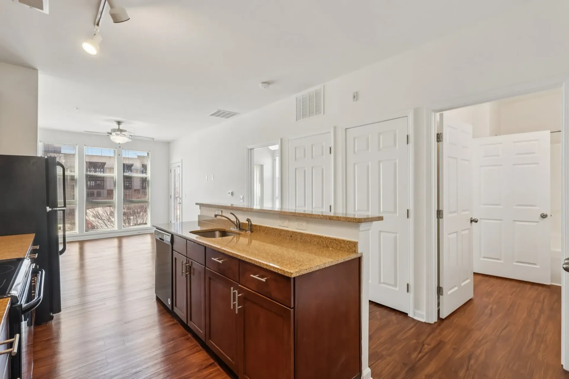 Modern kitchen with dark wood cabinets and granite countertops, open to living area.