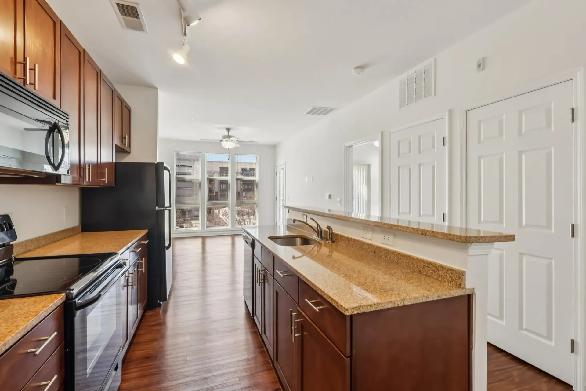 Modern kitchen with dark wood cabinets, granite countertops, and stainless steel appliances.
