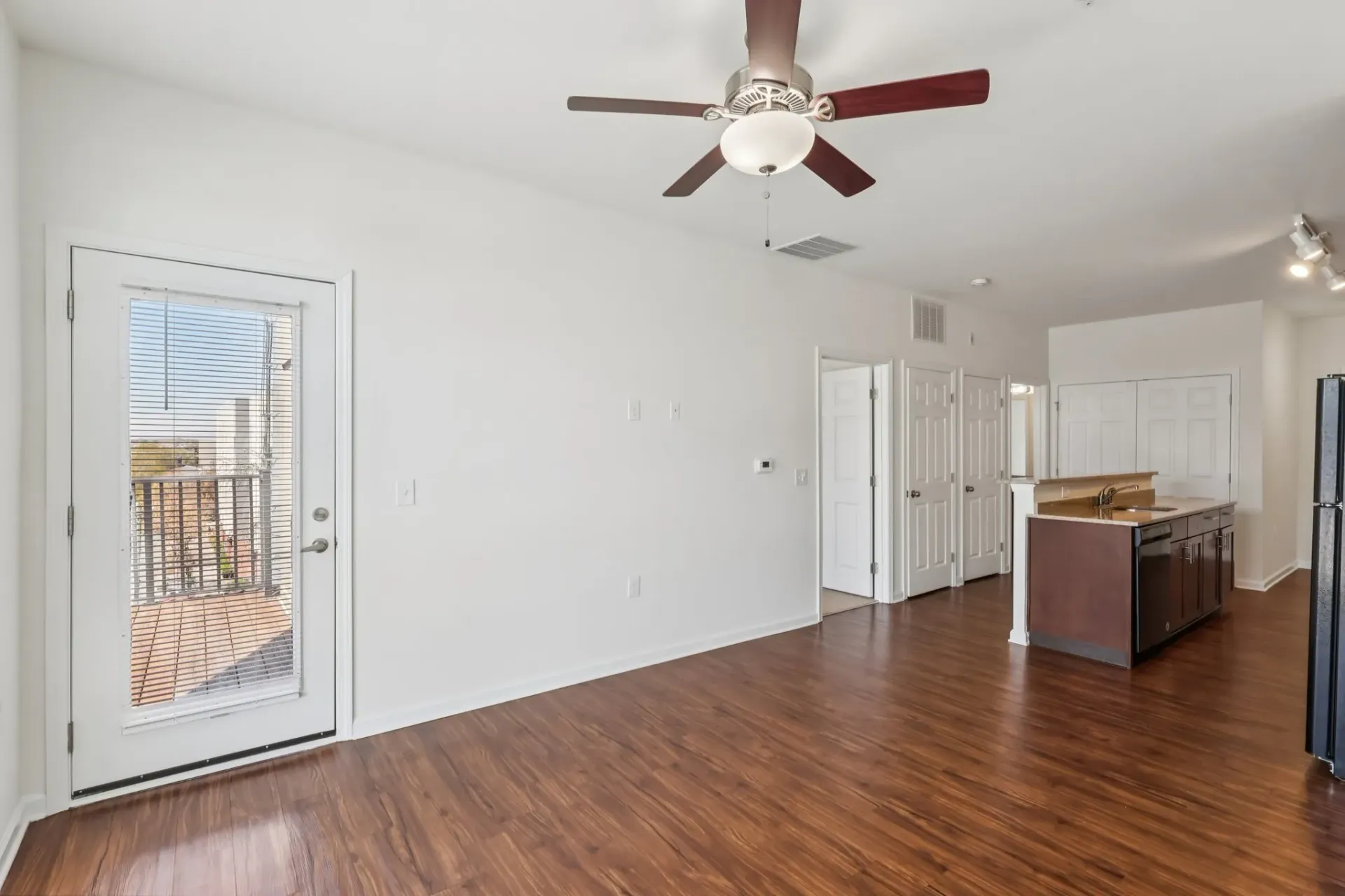 Living room and kitchen area with a ceiling fan, sliding glass door to balcony, and island counter.