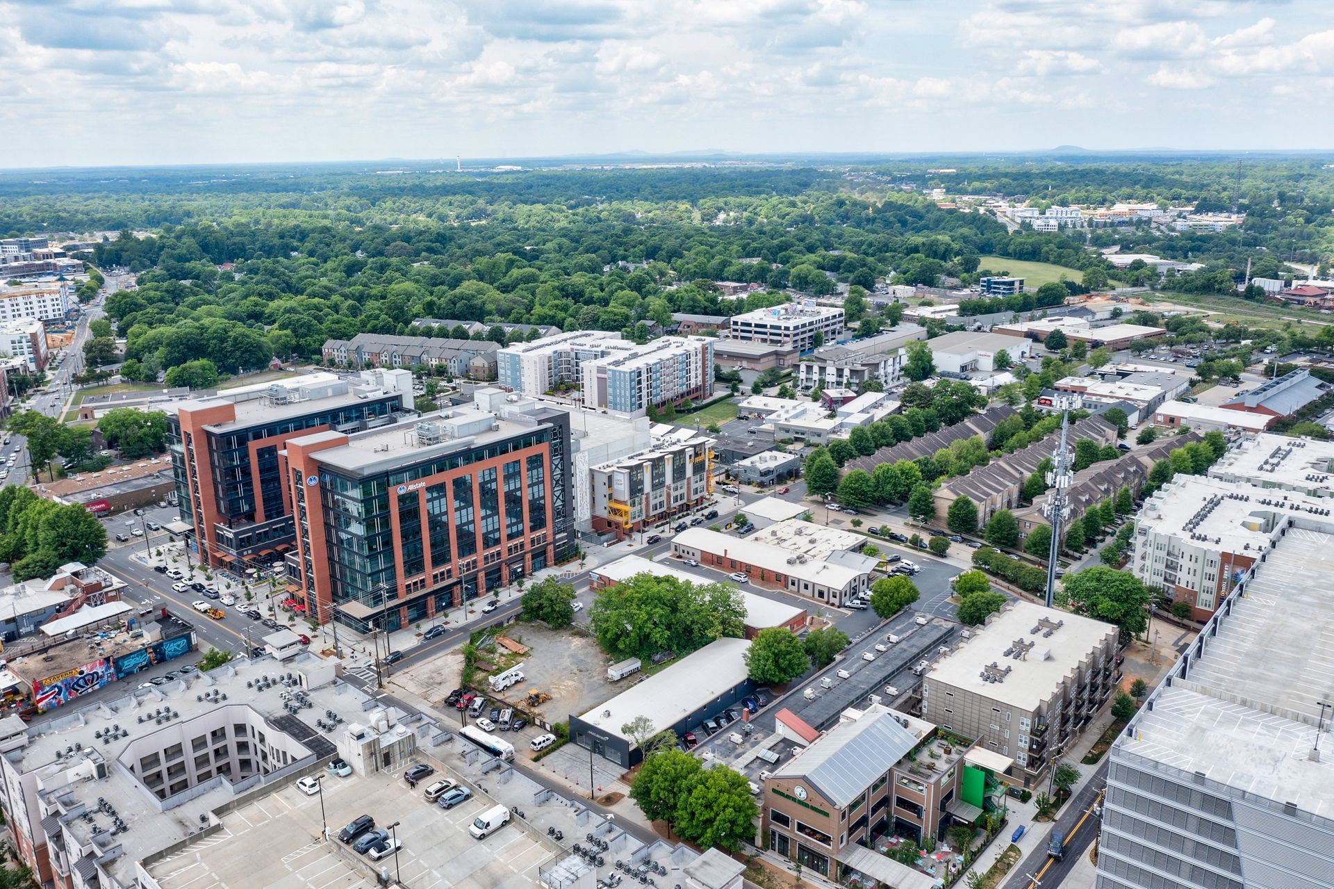 Aerial view of a city with tall brick buildings and green trees. Cloudy sky in the background.