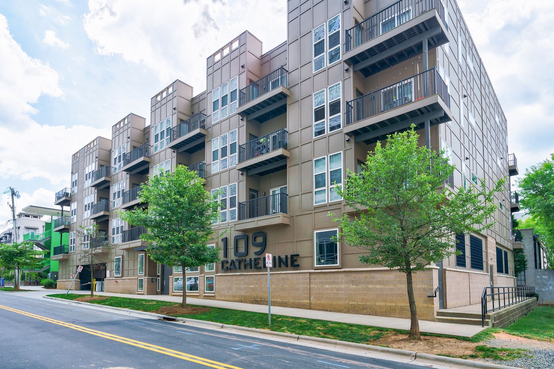 Modern apartment building at 109 Catherine with balconies and trees on the street.