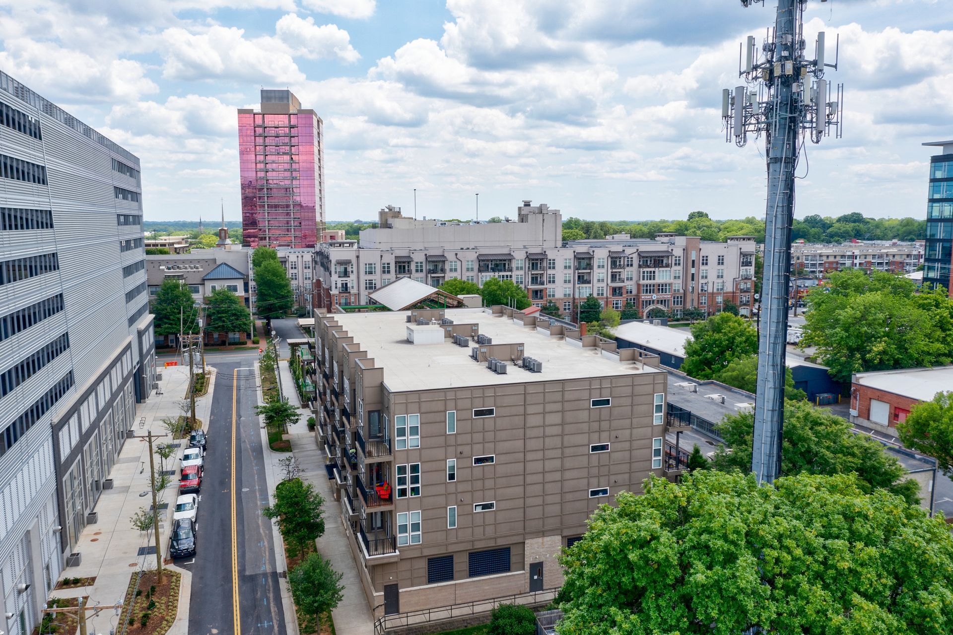 Cityscape with buildings of varying heights, pink tower, cell tower, blue sky.