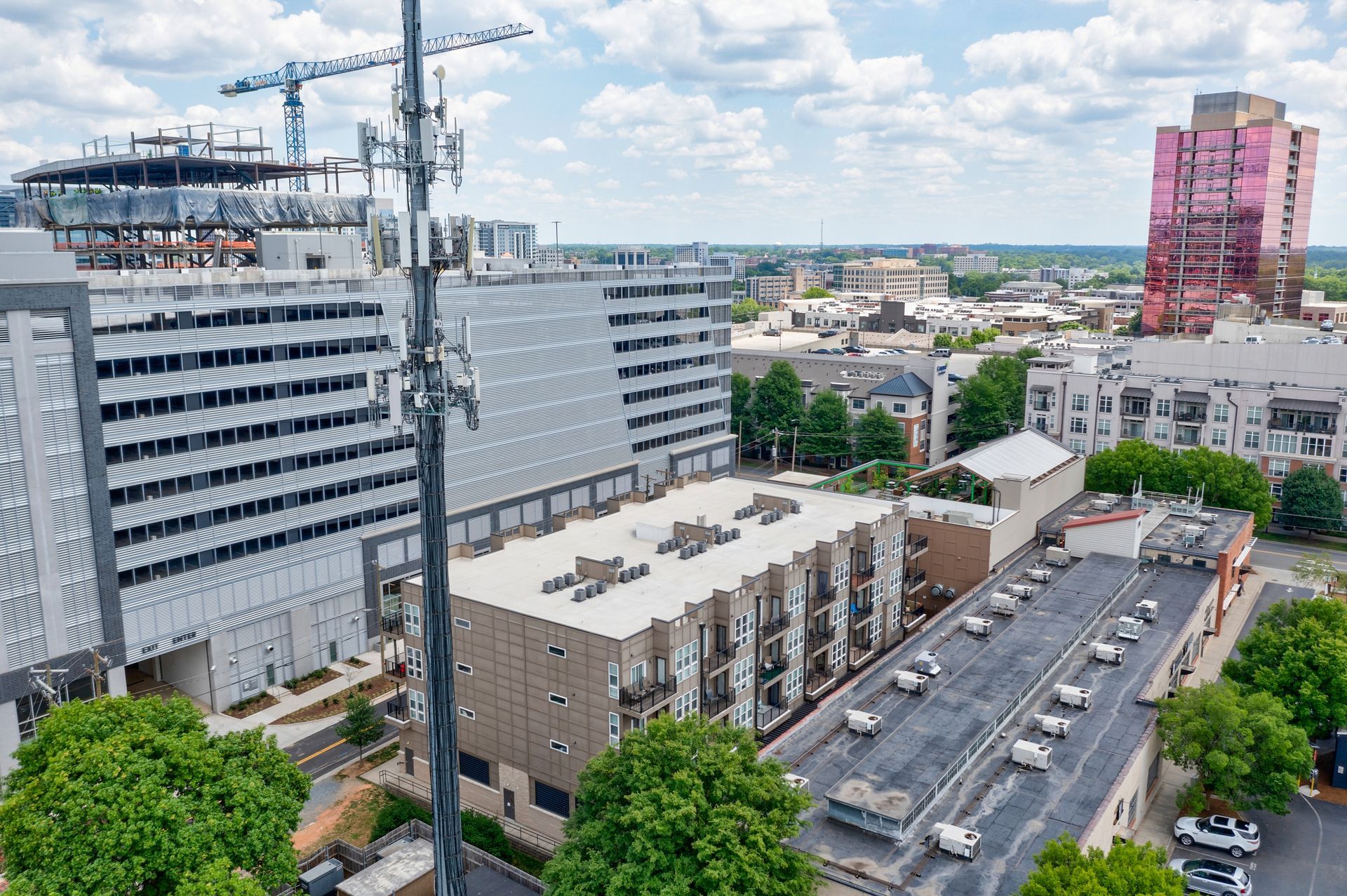 Cityscape with buildings, construction crane, pink tower, and cell tower.