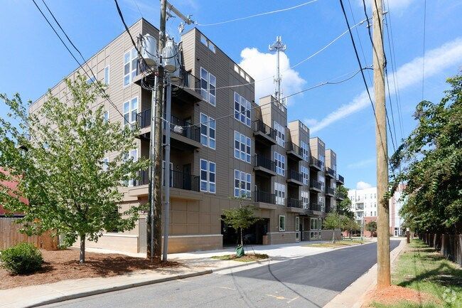 Apartment building on a street. Brown facade, balconies, blue sky, power lines.