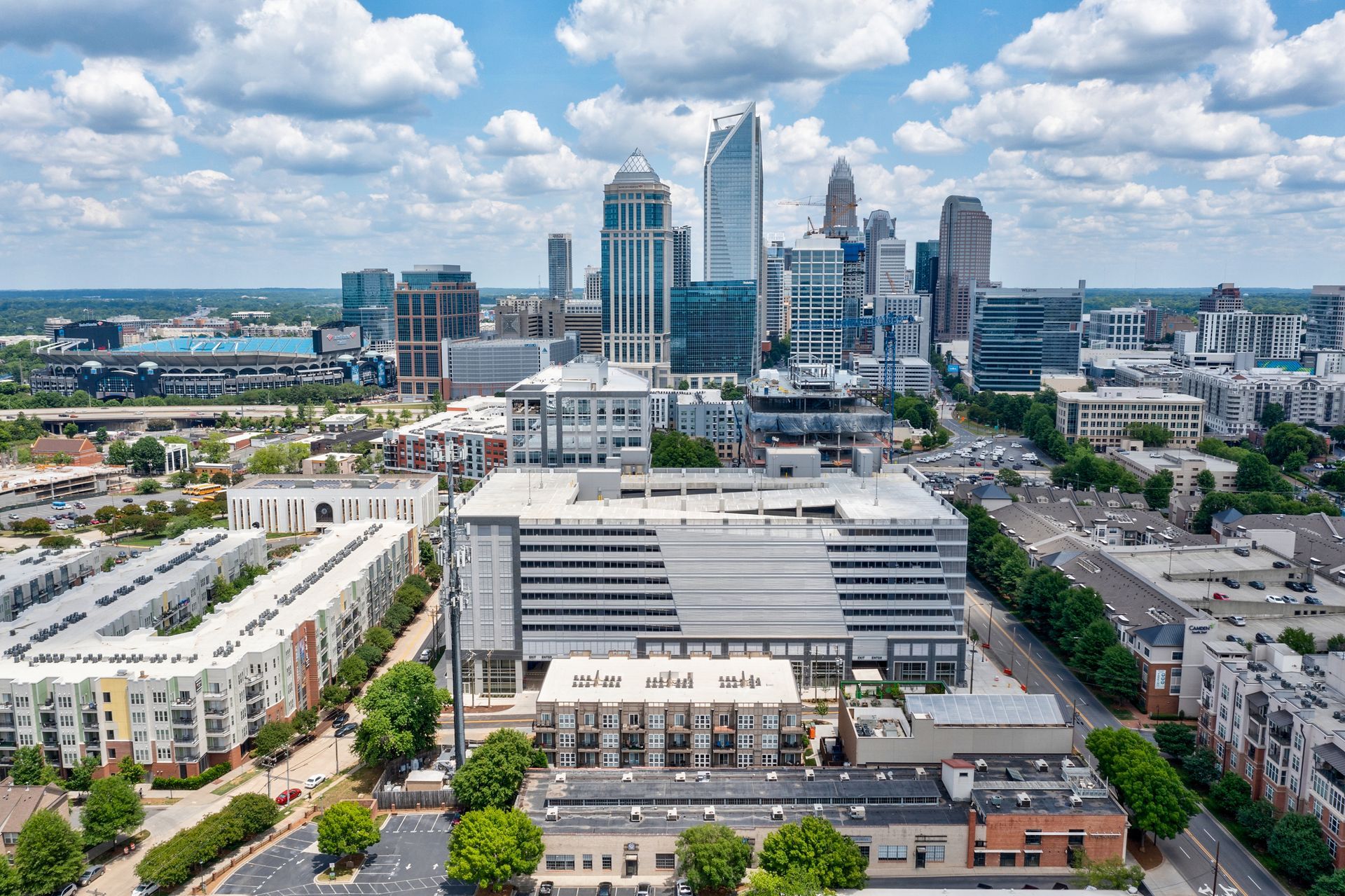 Aerial view of Charlotte, NC skyline with buildings and neighborhoods under a cloudy sky.