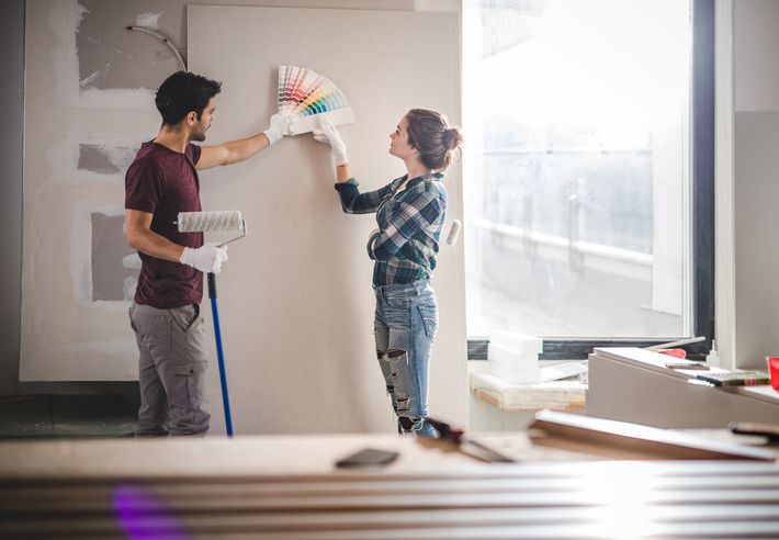 A man and a woman are painting a wall together.