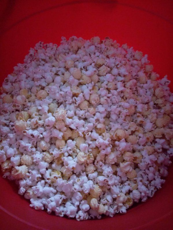 A red bowl filled with a large pile of freshly made popcorn