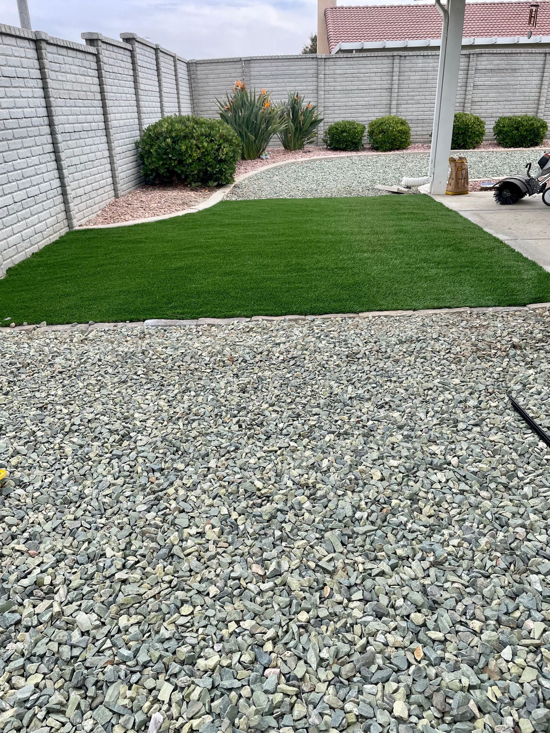 A gravel driveway with a lawn in the middle of it.