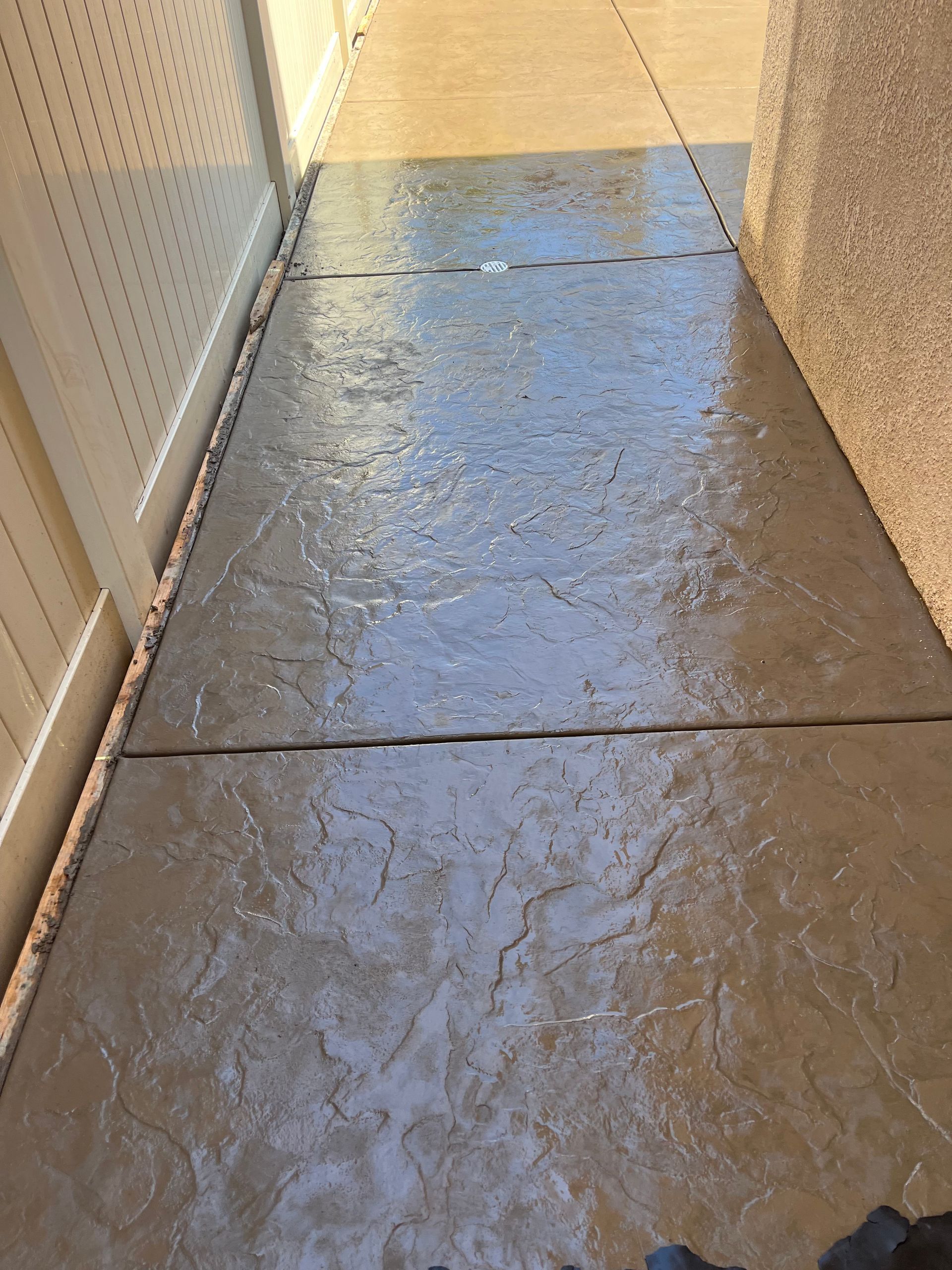Stamped concrete walkway with water droplets, leading from an exterior to an interior carpeted area.