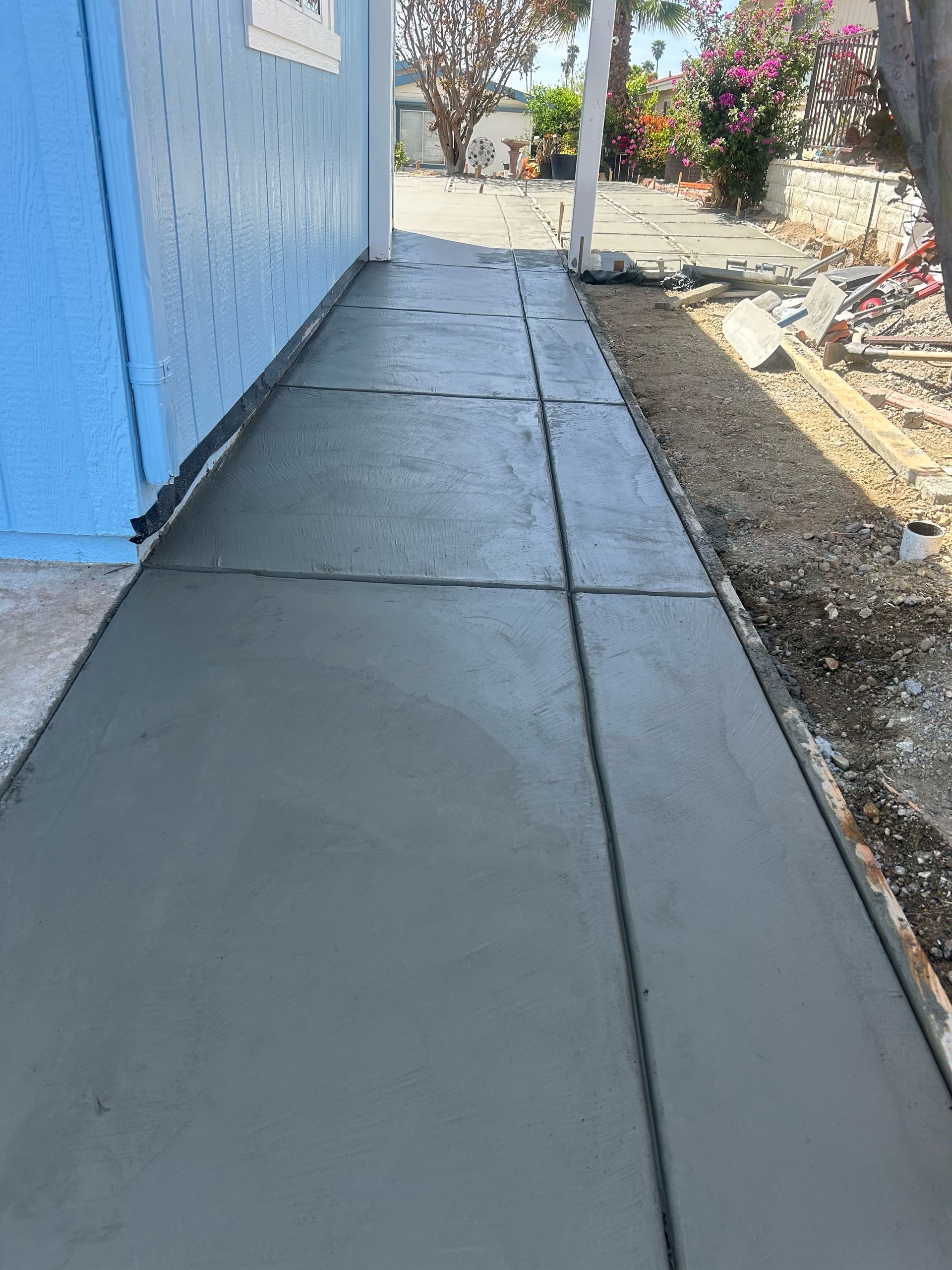 A concrete sidewalk is being built in front of a house.