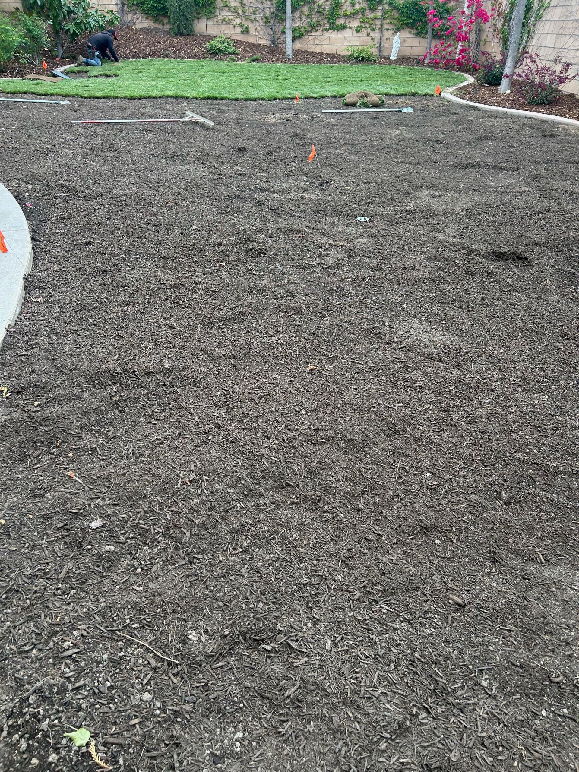 A person is standing on a pile of dirt in a yard.