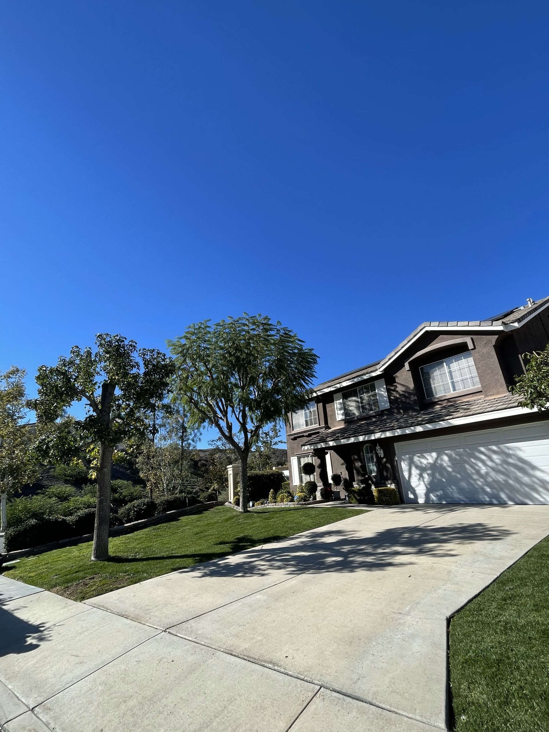 House with a brown roof and a white garage door, set on a bright day.