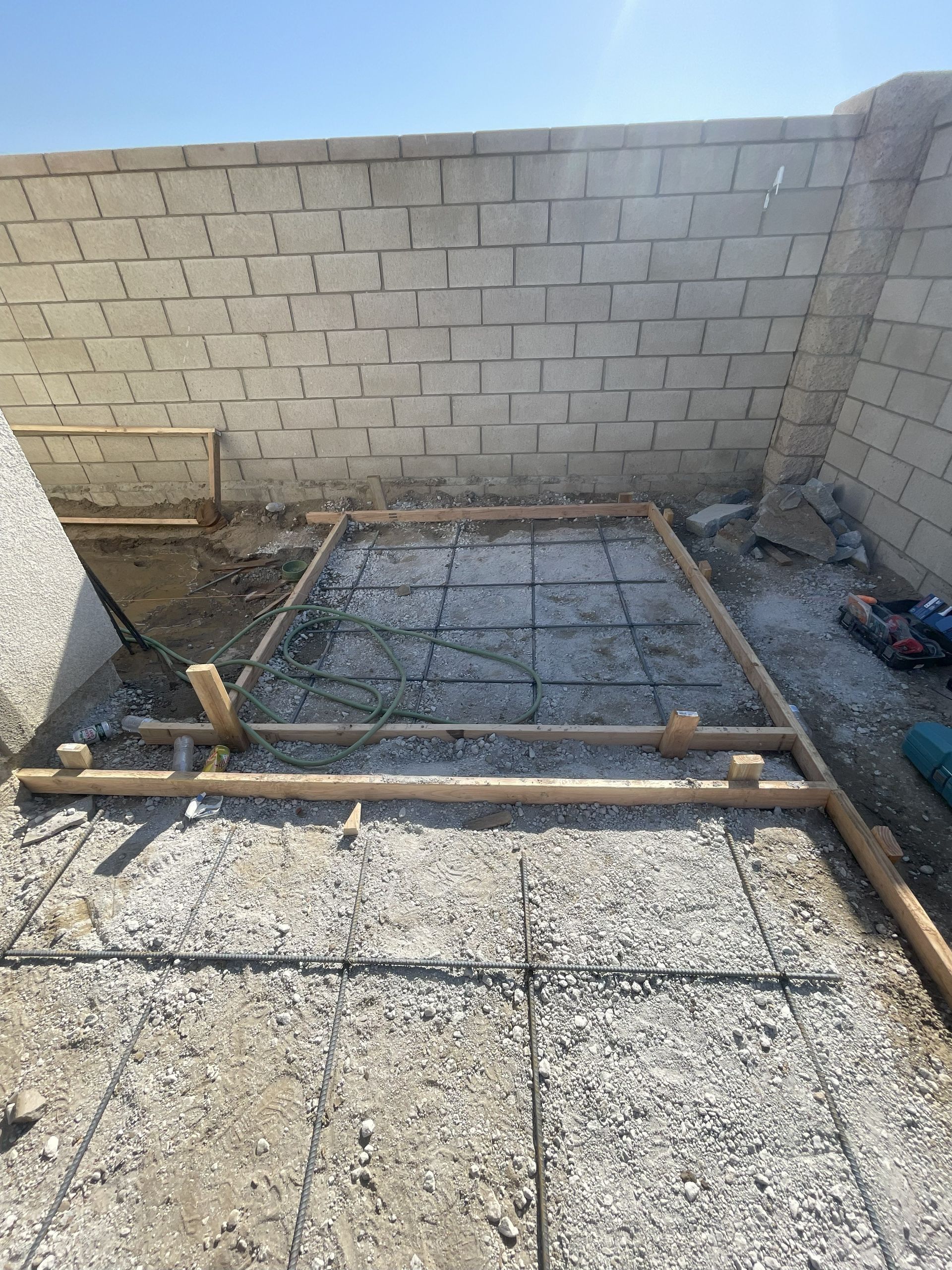 Concrete slab foundation framework with rebar, inside a block-walled area, ready for pouring.
