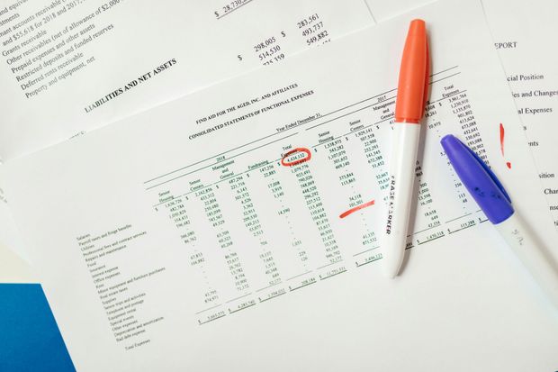 Paper documents with handwritten notes and circled numbers, alongside orange and purple markers.
