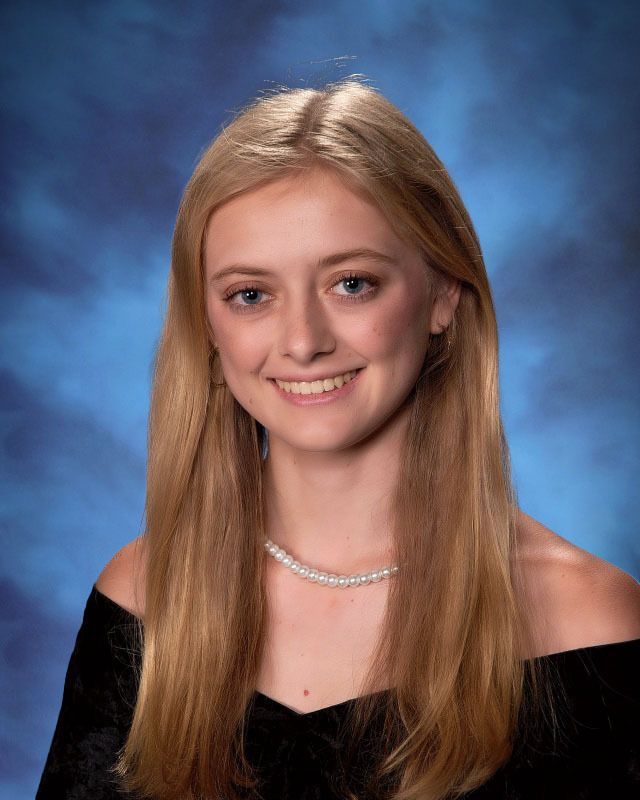 A young woman with long blonde hair is smiling for a picture.