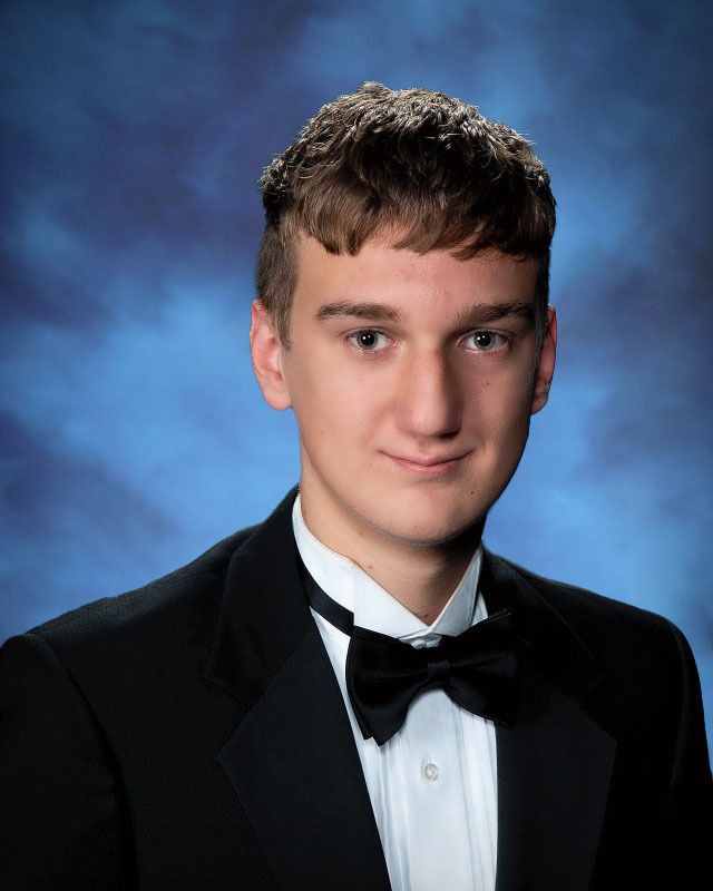 A young man in a tuxedo and bow tie poses for a picture