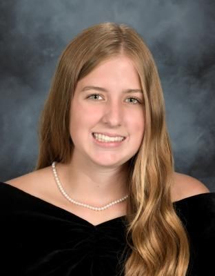 A young woman wearing a pearl necklace is posing for a picture.