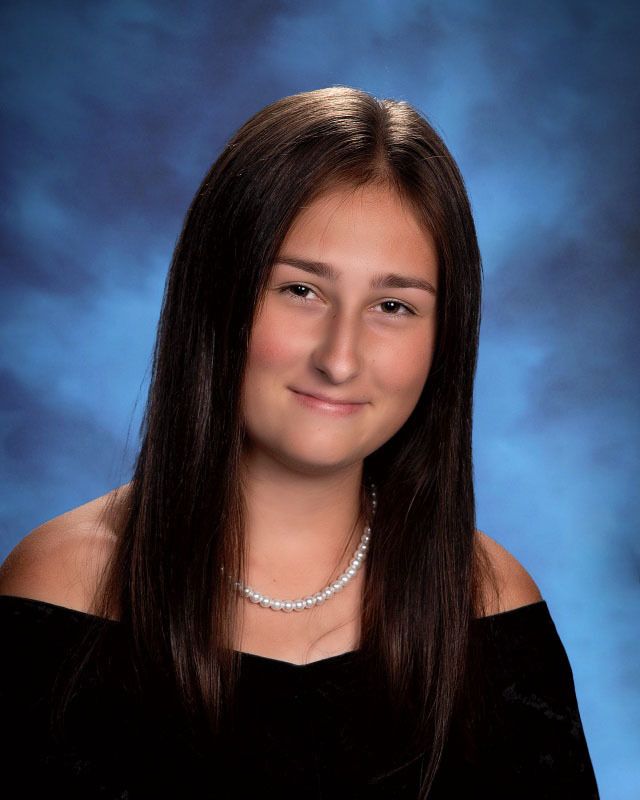 A young woman wearing a pearl necklace is posing for a picture.