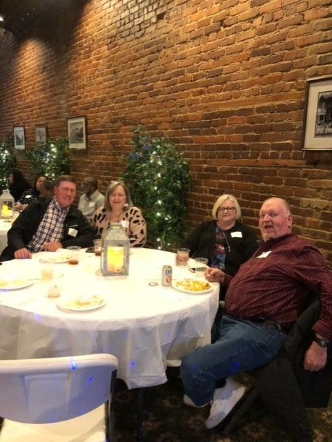 A group of people are sitting at tables in a room with a brick wall.