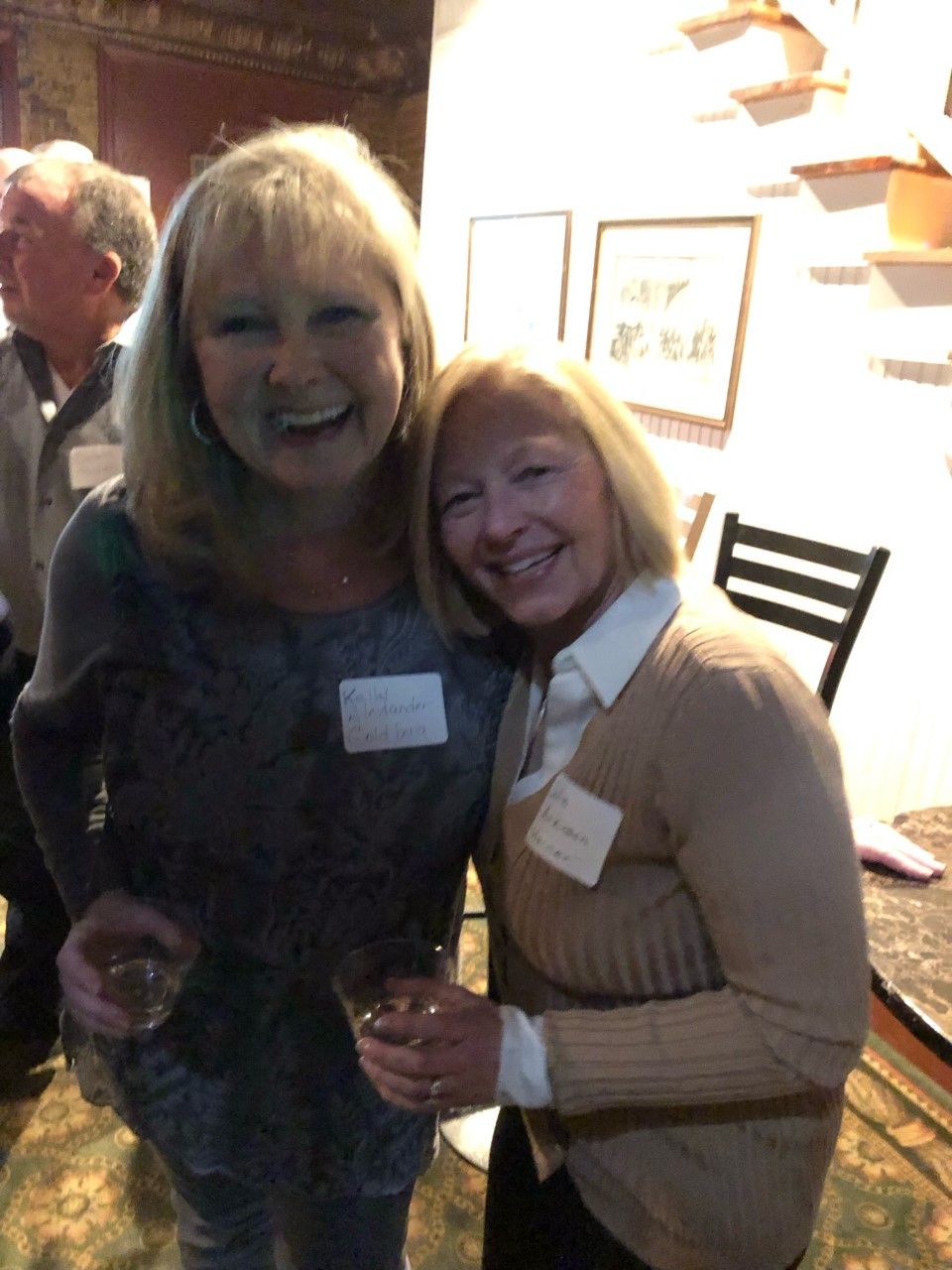 Two women are posing for a picture and one of them has a name tag on her shirt