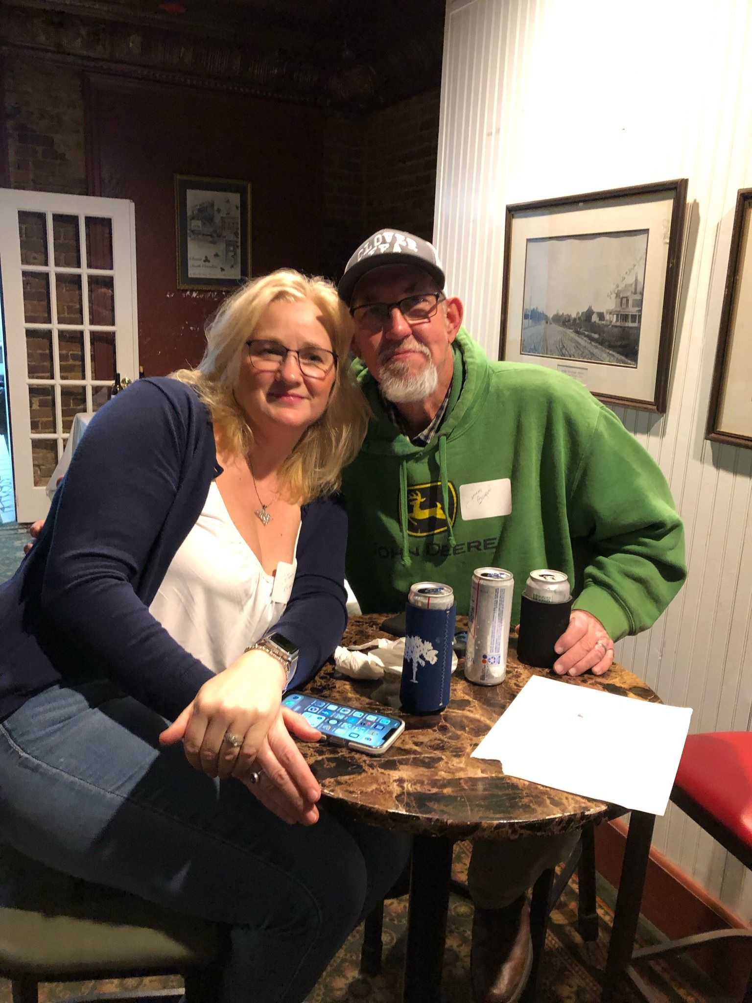 A man and a woman are sitting at a table with cans of beer.