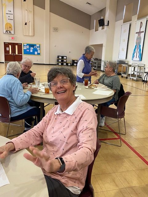 A group of older people are sitting at tables in a gym.