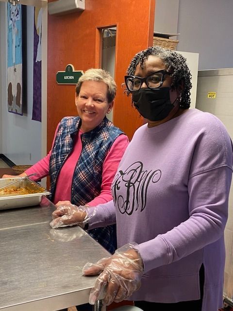 Two women wearing masks and gloves are standing next to each other