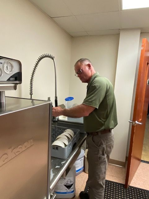 A man in a green shirt is washing dishes in a kitchen