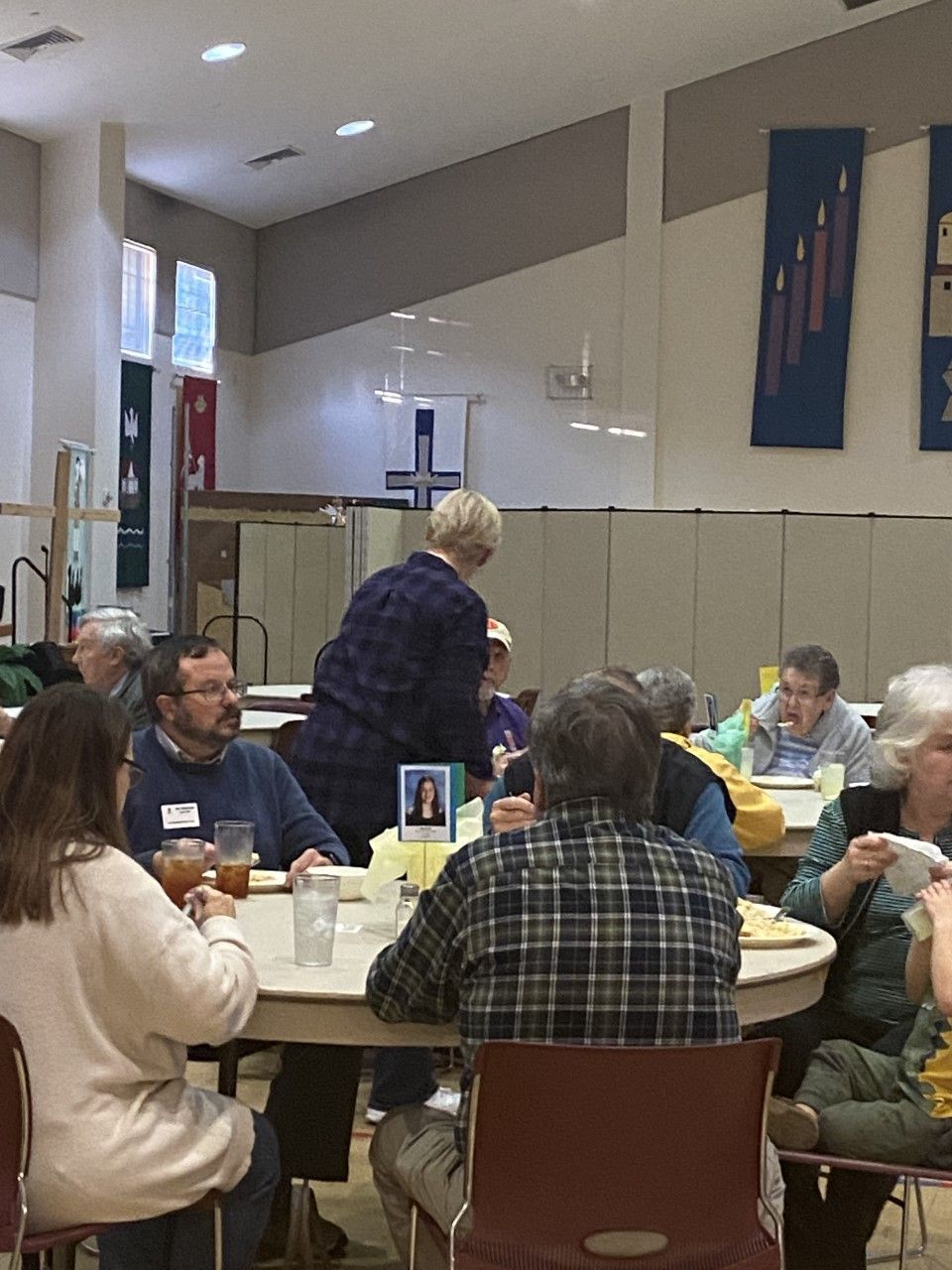 A group of people are sitting at tables in a room eating food.