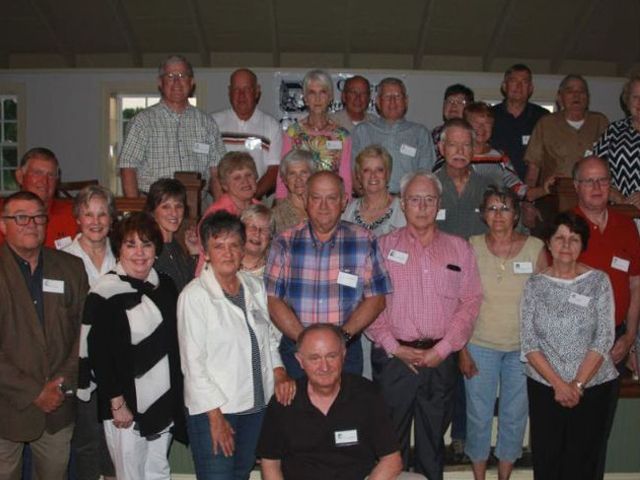 A group of people posing for a picture with one man wearing a name tag