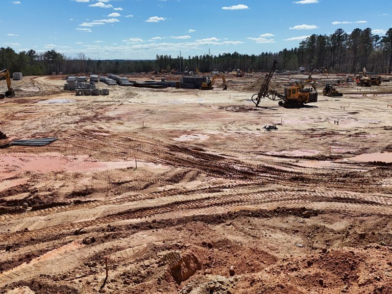 A large dirt field with a lot of tractors in it.