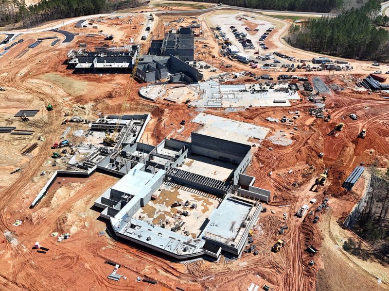 An aerial view of a large building under construction in the middle of a dirt field.