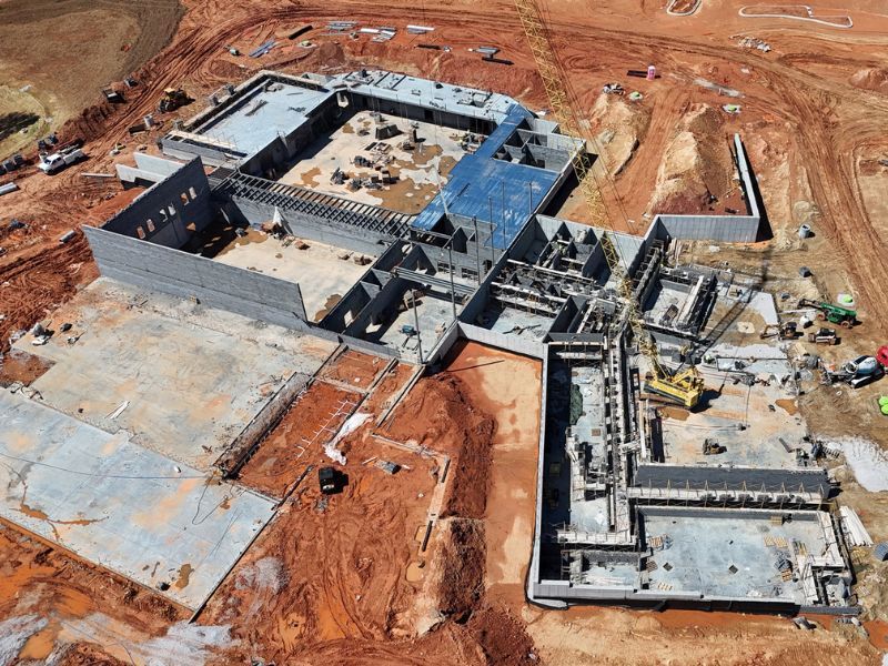 An aerial view of a building under construction in a dirt field.