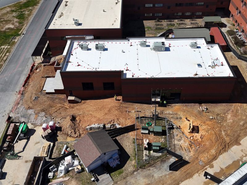 An aerial view of a building under construction with a white roof