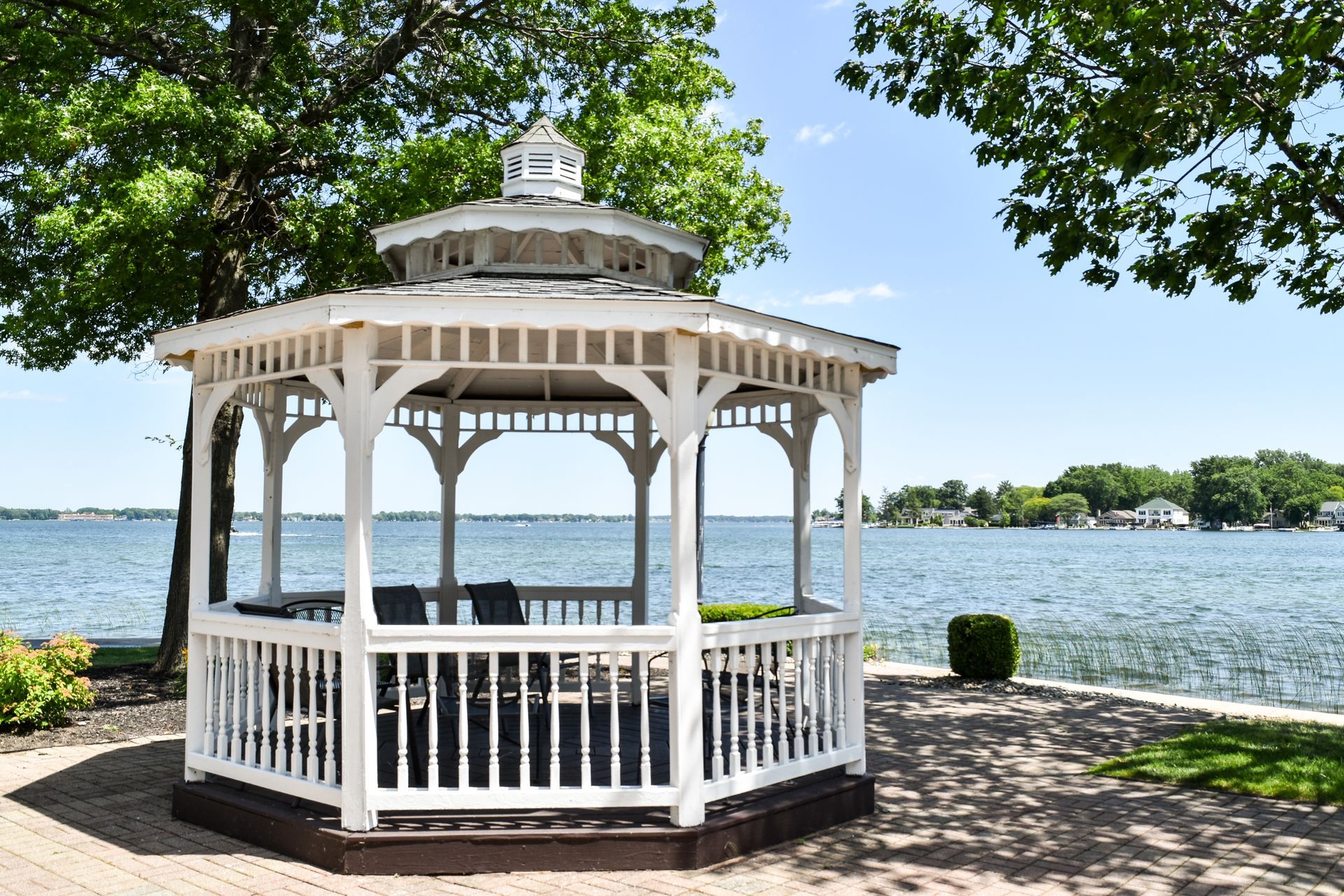 A white gazebo is sitting on the shore of a lake.