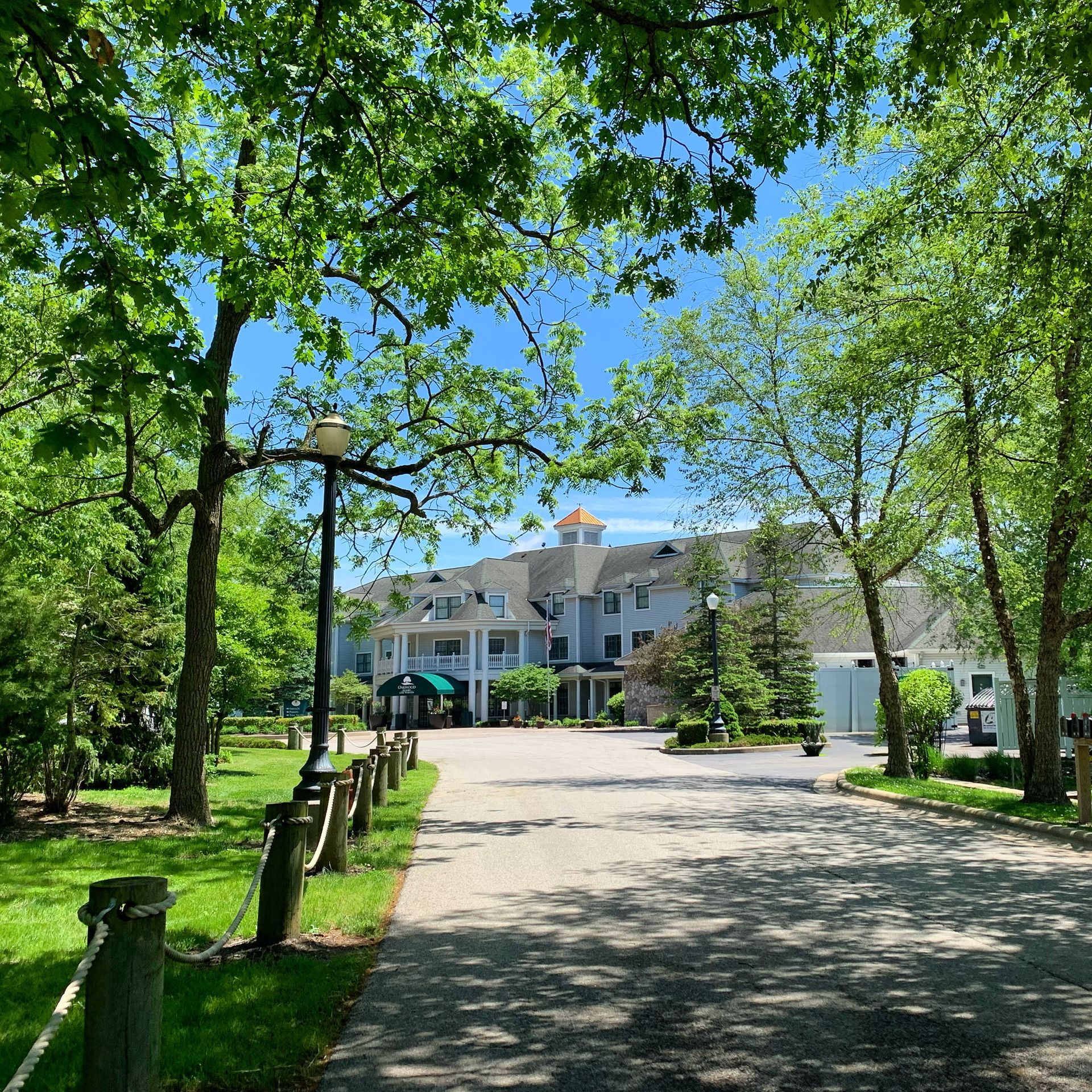 A large white house is surrounded by trees on a sunny day