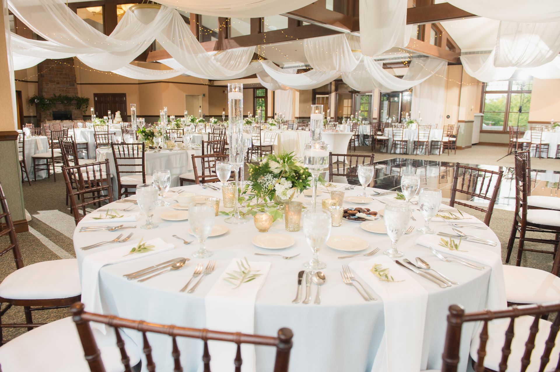 A large room with tables and chairs set up for a wedding reception.