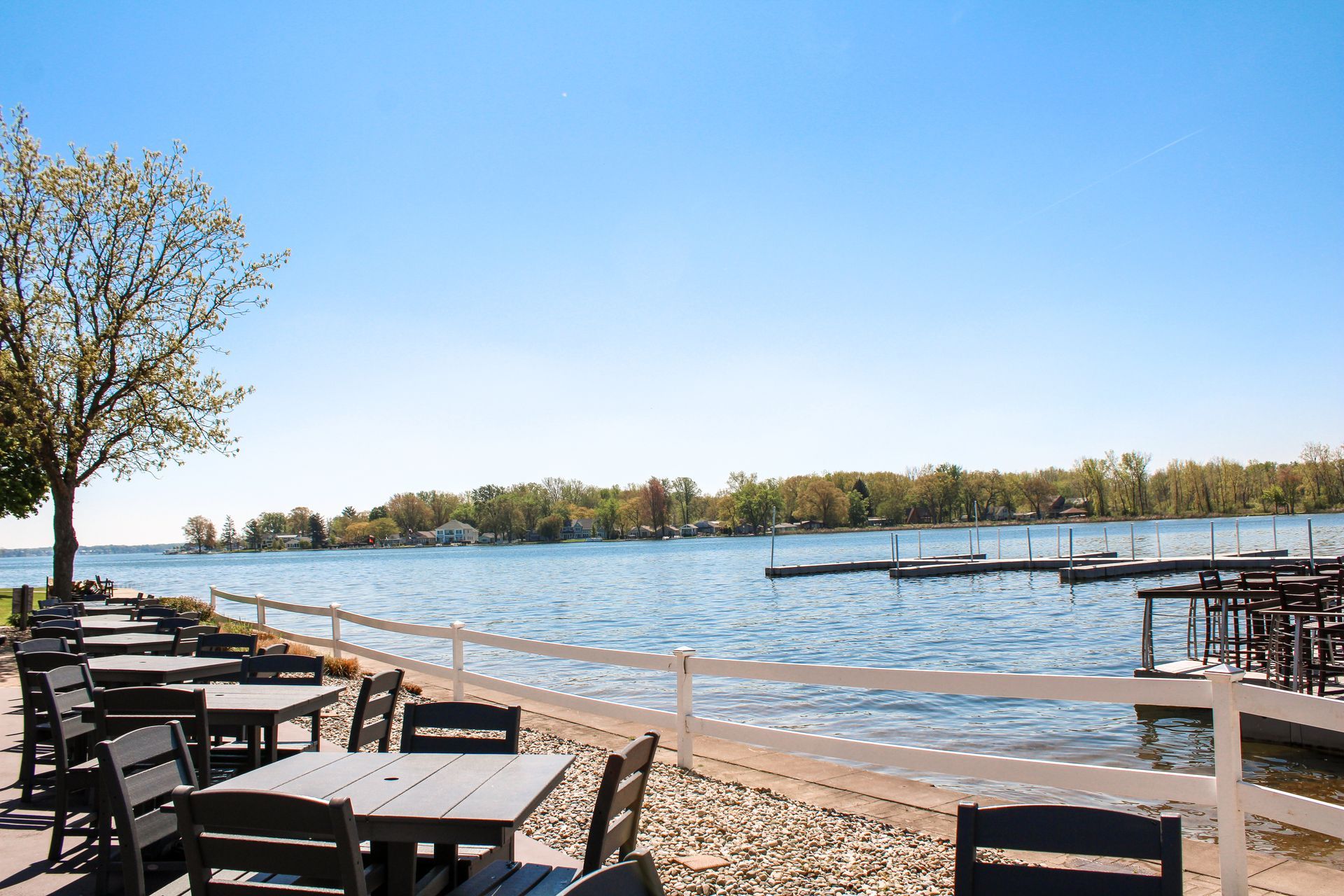 A row of tables and chairs on the shore of a lake.