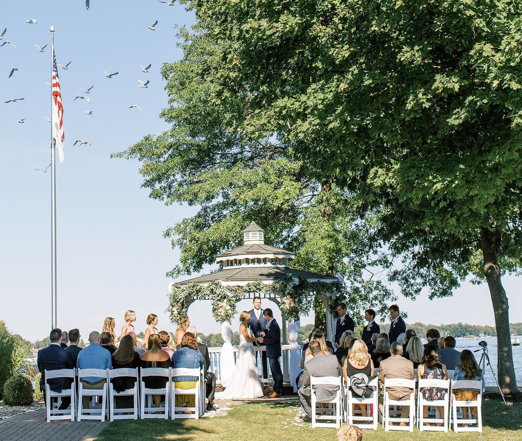 A bride and groom are getting married in a gazebo in front of a crowd of people.