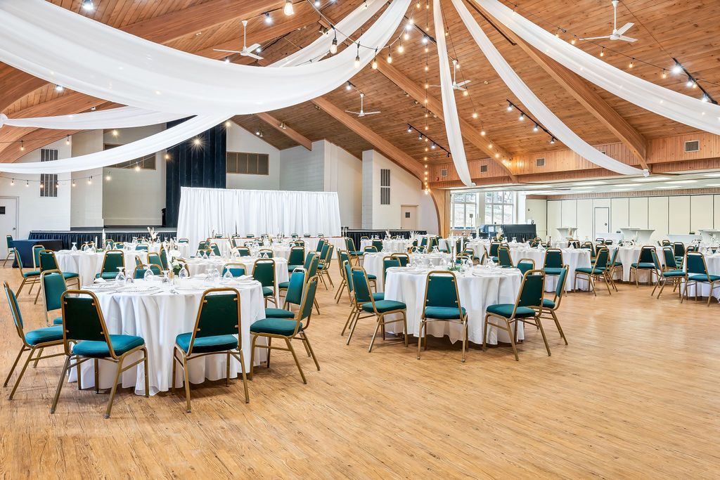 A large room with tables and chairs set up for a wedding reception.