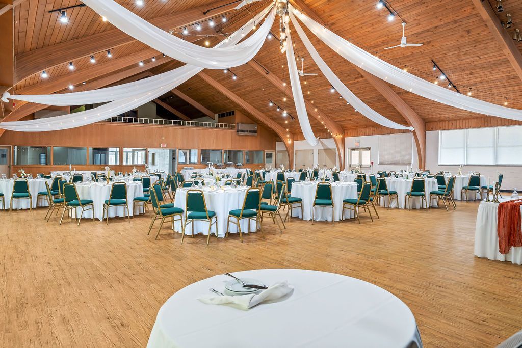 A large room with tables and chairs set up for a wedding reception.