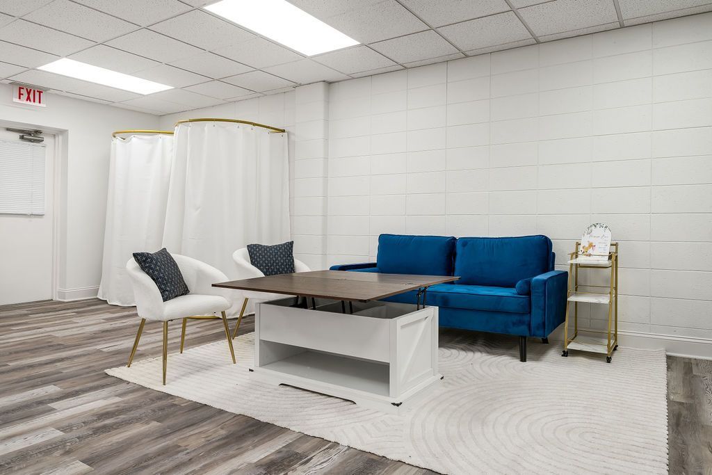 A living room with a blue couch , table and chairs.