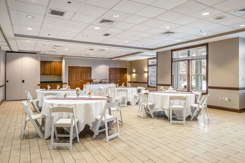 A large room with tables and chairs set up for a wedding reception.